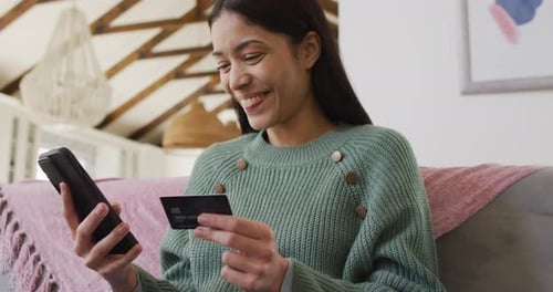 Young Woman Using Phone and Credit Card at Home