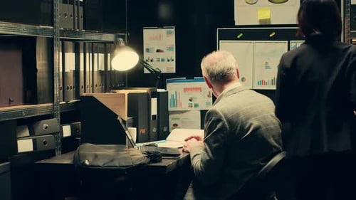 Teamwork Reviewing Document at Desk in Dark Office