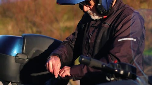 Elderly man putting on leather gloves before riding his motorcycle