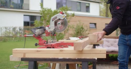 Man Cuts Wood with Power Saw in Yard