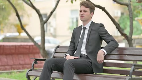 Man with Back Pain Sitting on Park Bench