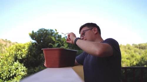 A Man Smiles While Holding a Potted Plant on His Balcony Enjoying the Outdoor Environment Slow