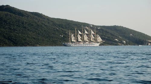 Slow motion of antique sailship with white sails and high mast sailing in the sea at sunset.