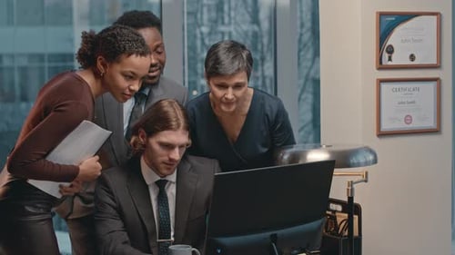 Team of Coworkers Looking at Computer and Discussing Business Project