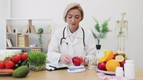 Woman Doctor Weighs Apple at Her Desk