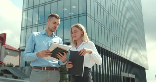 Man and Woman Outside a Business Center Talking About Work