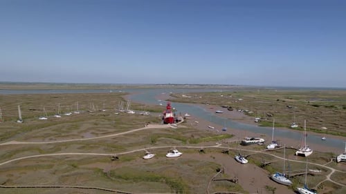 Aerial view towards a light ship stuck in mud at low tide, sunny Tollesbury, UK - approaching, drone