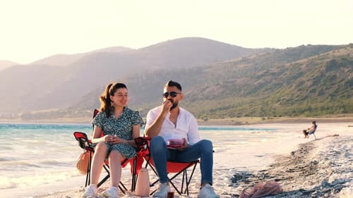 Happy Couple Sitting On The Beach