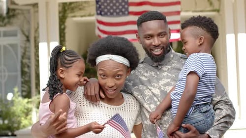 Smiling Family Poses with American Flag Outside Home