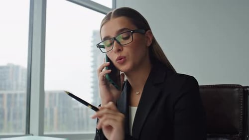 Focused woman manager speaking on phone with client in modern office
