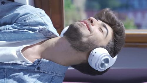 Young Man Relaxes Listening to Music with Headphones