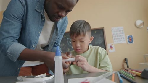 Joyous Asian Boy Making Paper Craft with School Teacher