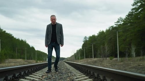 Man Walks on Train Tracks in Rural Area