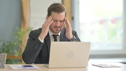 Stressed Businessman Working on Laptop in Office