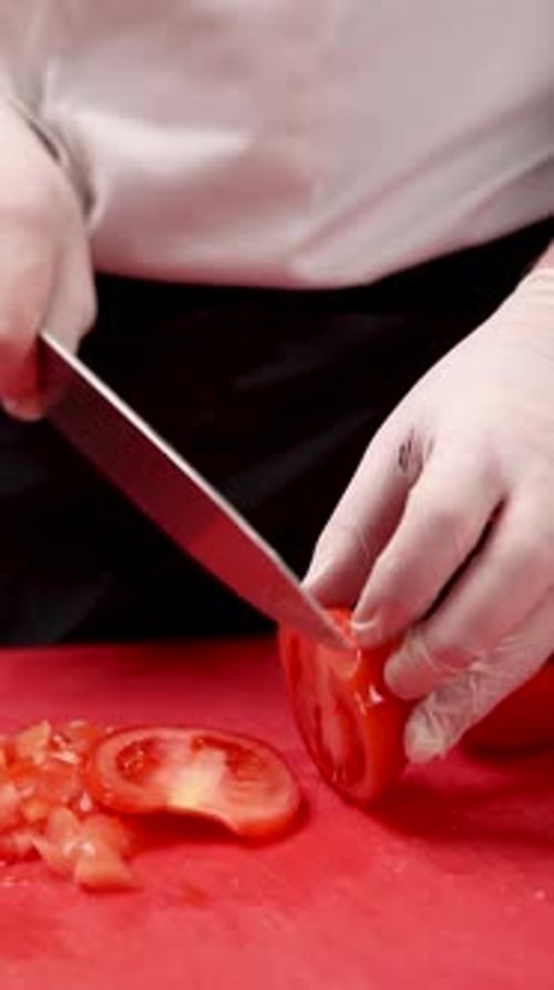 chef cuts tomatoes on a red cutting board