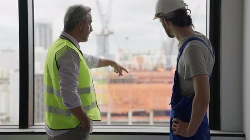 Engineer Contractor Working with Young Electrician on New Building