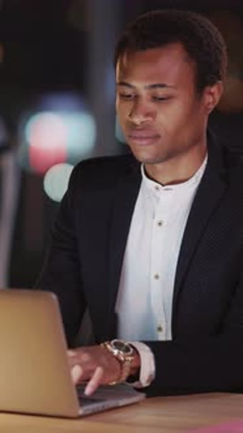 A Professional Man is Working on a Laptop at Night in the City Immersed in His Tasks