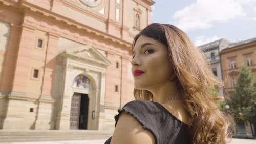 A Young Caucasian Woman Looks Over Her Shoulder in Thought in an Urban Area a Quaint Church