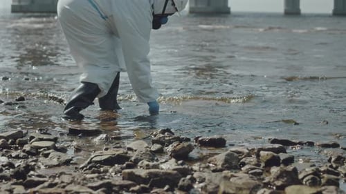 Scientist Taking Water Sample Near Bridge