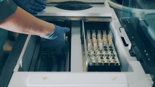 Lab Technician Places Test Tubes into Machine