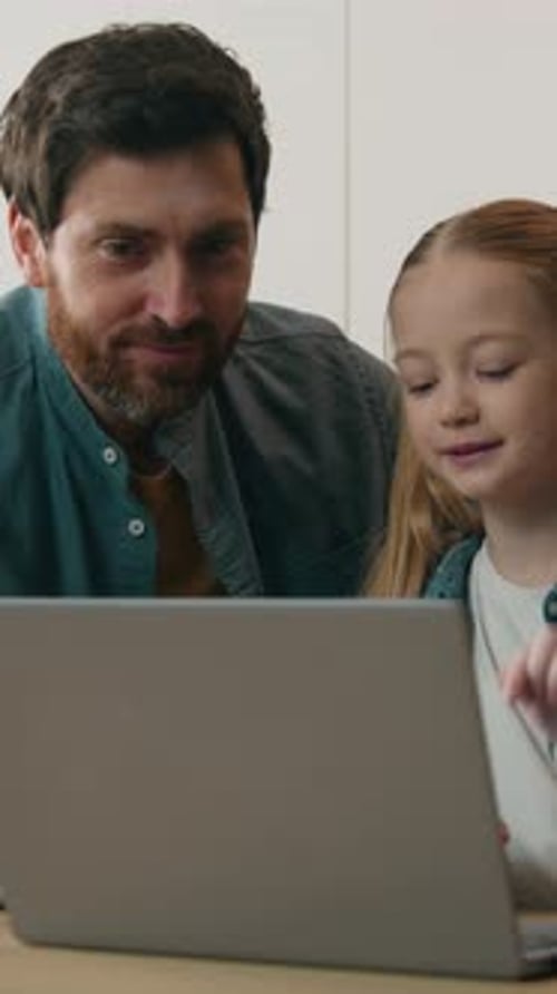 Bearded man and young girl using laptop together