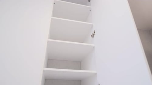 Stylish large white cabinet from floor to ceiling. Open doors in the closet, shelves. Furniture in t