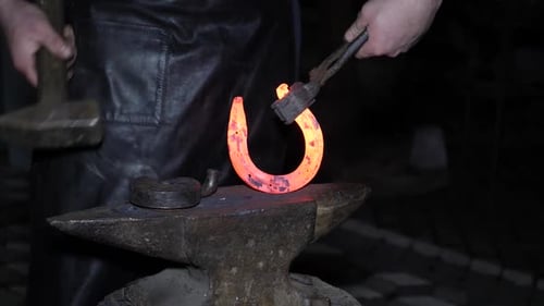 Blacksmith Shaping Hot Metal on Anvil at Night