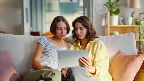 Two Young Women Relaxing at Home with Tablet
