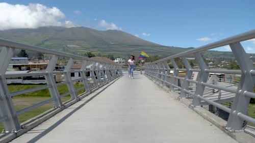 Woman Runs on Bridge Waving Flag, Mountain Backdrop