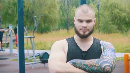 Ein starker bärtiger Mann mit Tattoos, der auf dem Sport steht