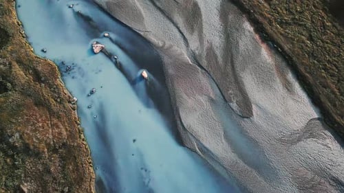 Fast and ascending aerial view over colorful river in mountains. Natural landscape. Melt water flows