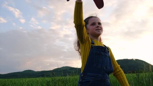 Close up of playful little girl playing with toy airplane on background sky and mountains