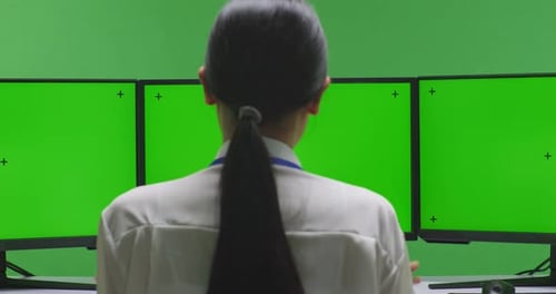 Asiatische Frau hat Video mit nachgebildertem Mehrcomputermonitor im Greenscreen-Studio