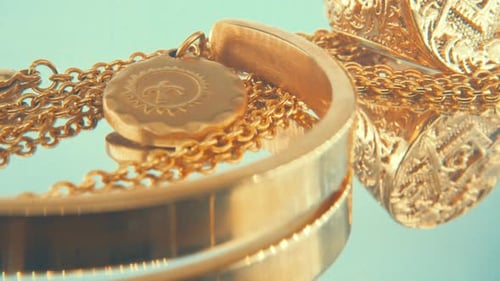 Drehbare Makroaufnahme einer Goldmedaillon-Halskette, goldenes Armband mit goldenem Ring, auf einem
