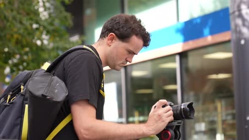 Man Setting Up Camera On Tripod Outdoors