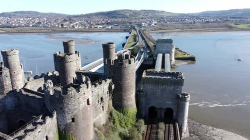 Medieval Conwy castle Welsh market town ruins aerial view historical harbour slow descend left