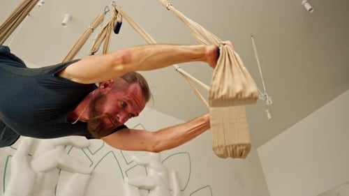 Man Practicing Aerial Yoga In Indoor Studio
