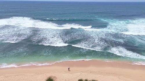 Walking on the shore of the beach where the turquoise sea waves break on the sand.