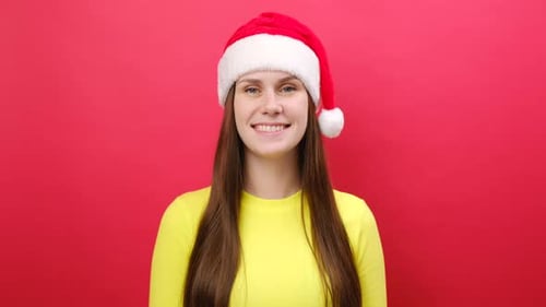 Smiling Woman in Santa Hat Against Red Backdrop
