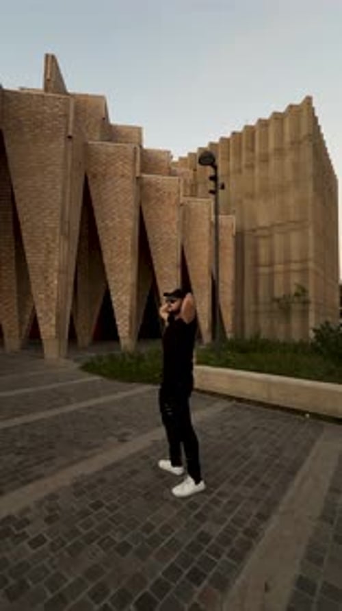 Man posing near geometric modern architecture in urban evening setting