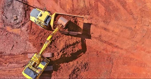 Excavator Loads Soil Into Dump Truck From Above