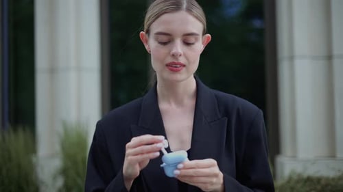 Confident Businesswoman Wearing Earphones Near Big Modern Business District