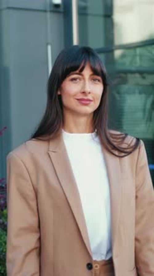 Young and Smiling Businesswoman Standing Outdoors in the City Posing for the Camera with Her Arms