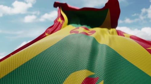 Realistic Grenada Flag Waving Against a Clear Blue Sky