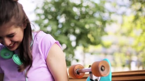 Teen Girl Laughing at Phone Outdoors with Skateboard