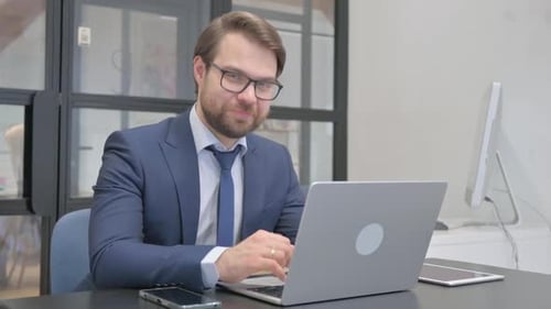 Thumbs Up by Young Businessman Looking at Camera in Office