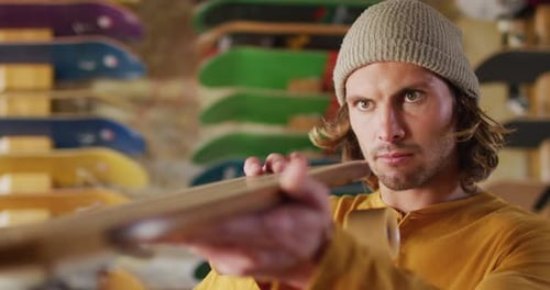 Video of caucasian male skateboarder fixing skateboard in skate shop