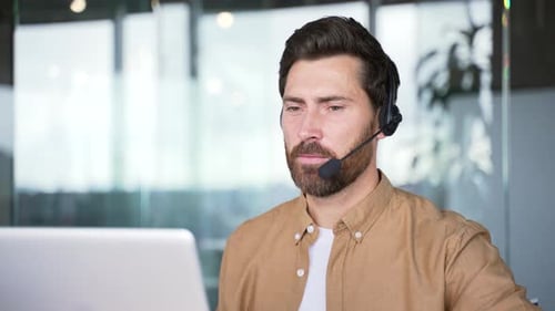 Corporate operator who works in customer support speaks on a video call using a laptop. Call center