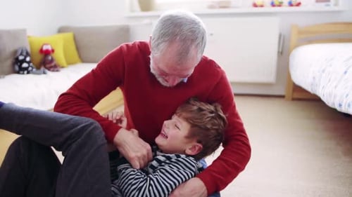Grandfather and Grandson Playfully Tussling on Floor
