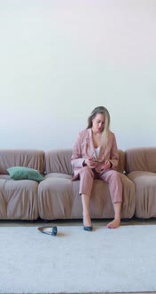 Vertical Footage of Businesswoman Sits on a Sofa in the Living Room and Falls Down After a Hard Day